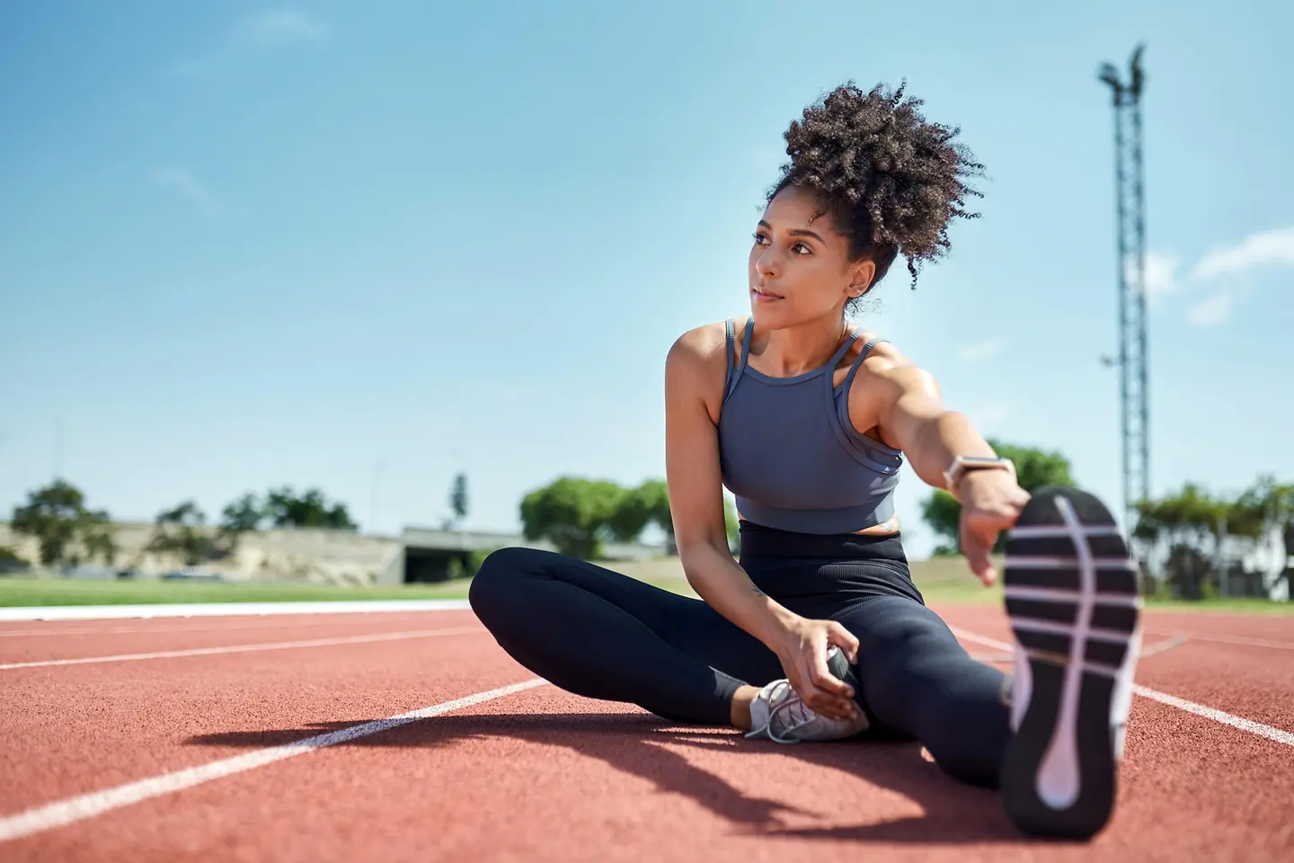 Eine junge Frau macht Dehnübungen auf einem Sportplatz