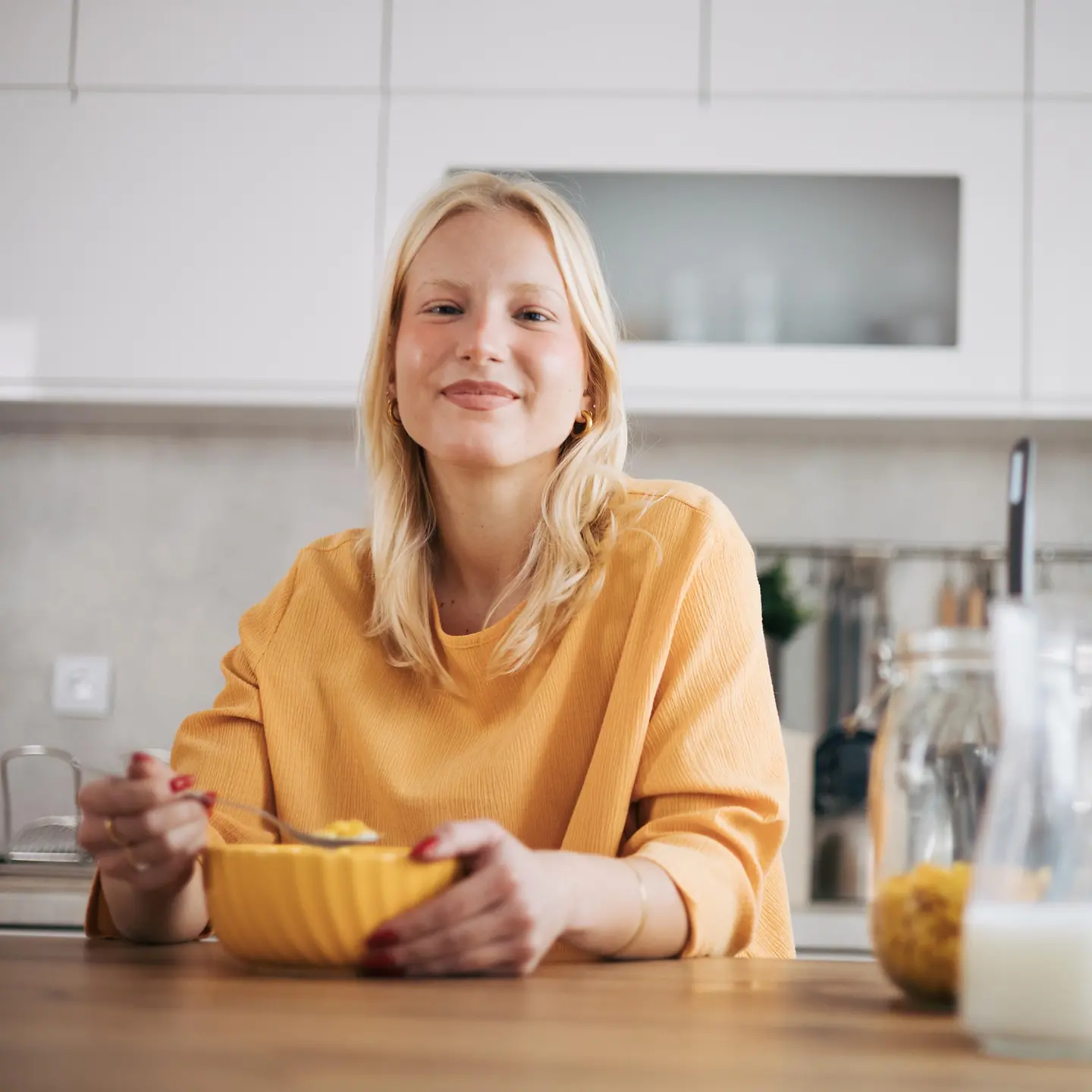 Junge, blonde Frau genießt ihr Frühstücksmüsli in der Küche