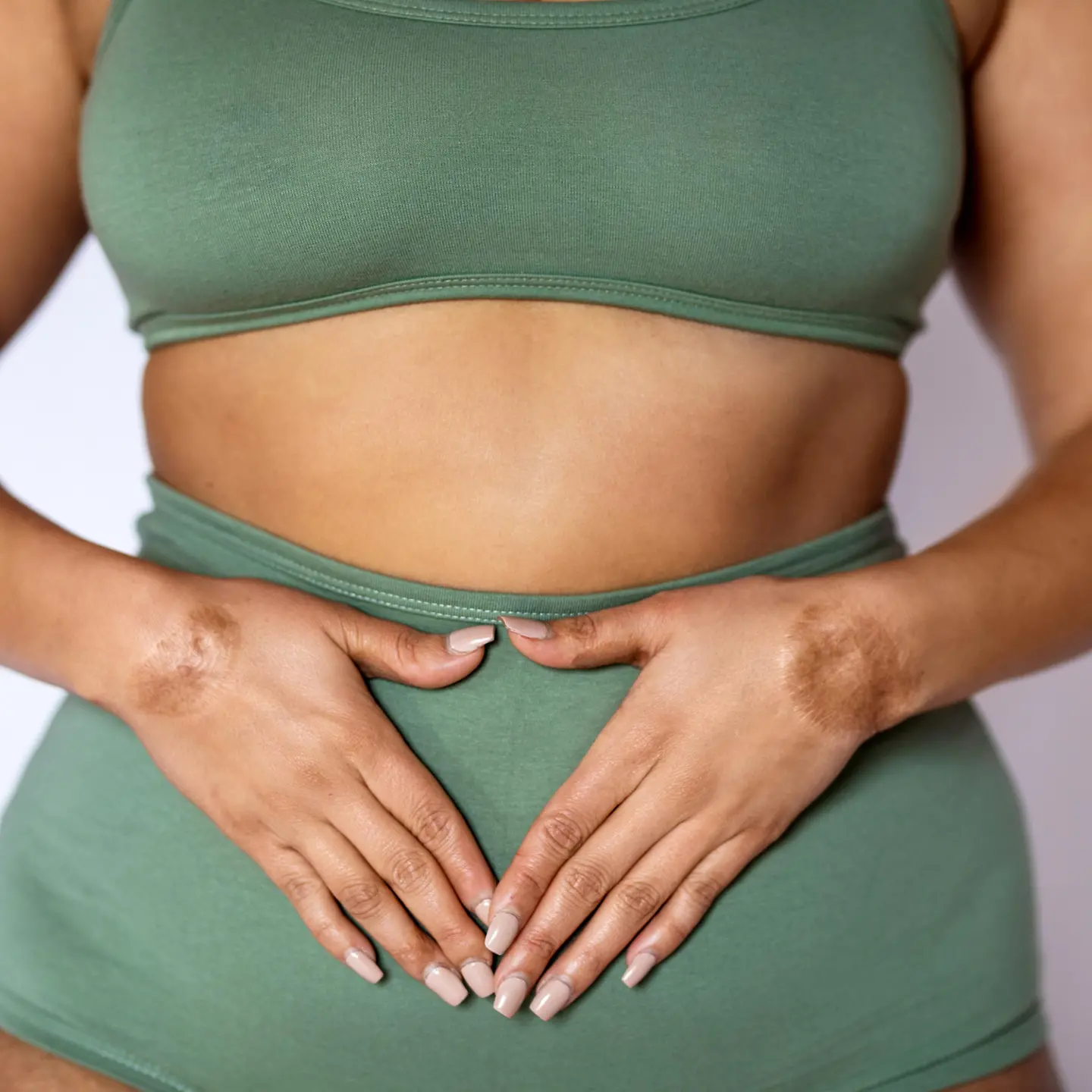 Ausfluss vor der Periode: Frau in Unterwäsche, die ihre Hände auf ihren Bauch legt