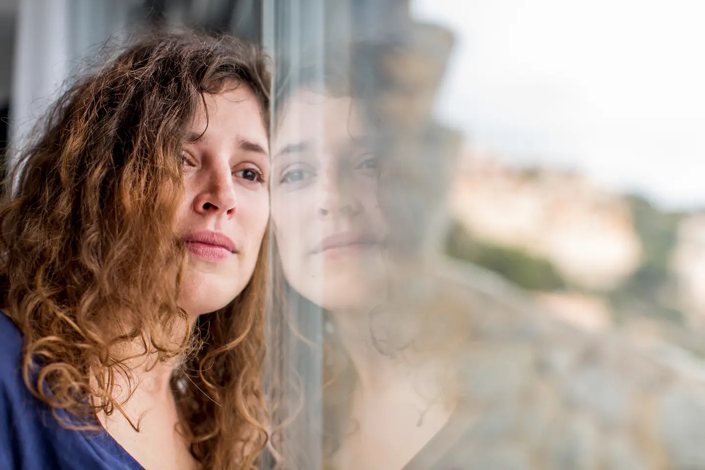 Eine junge Frau traurig schaut aus dem Fenster und weint