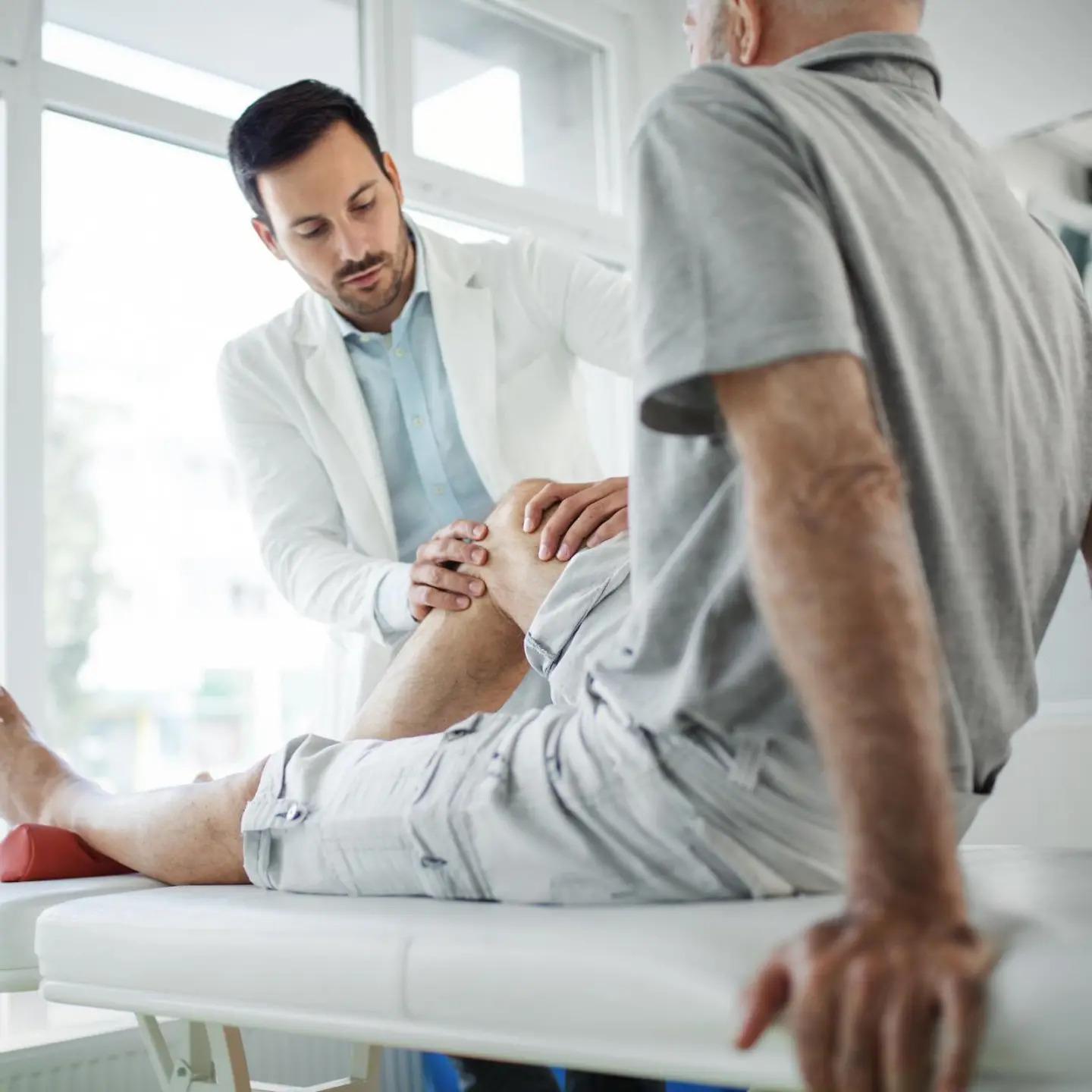 Ein Arzt untersucht das Knie eines Mannes