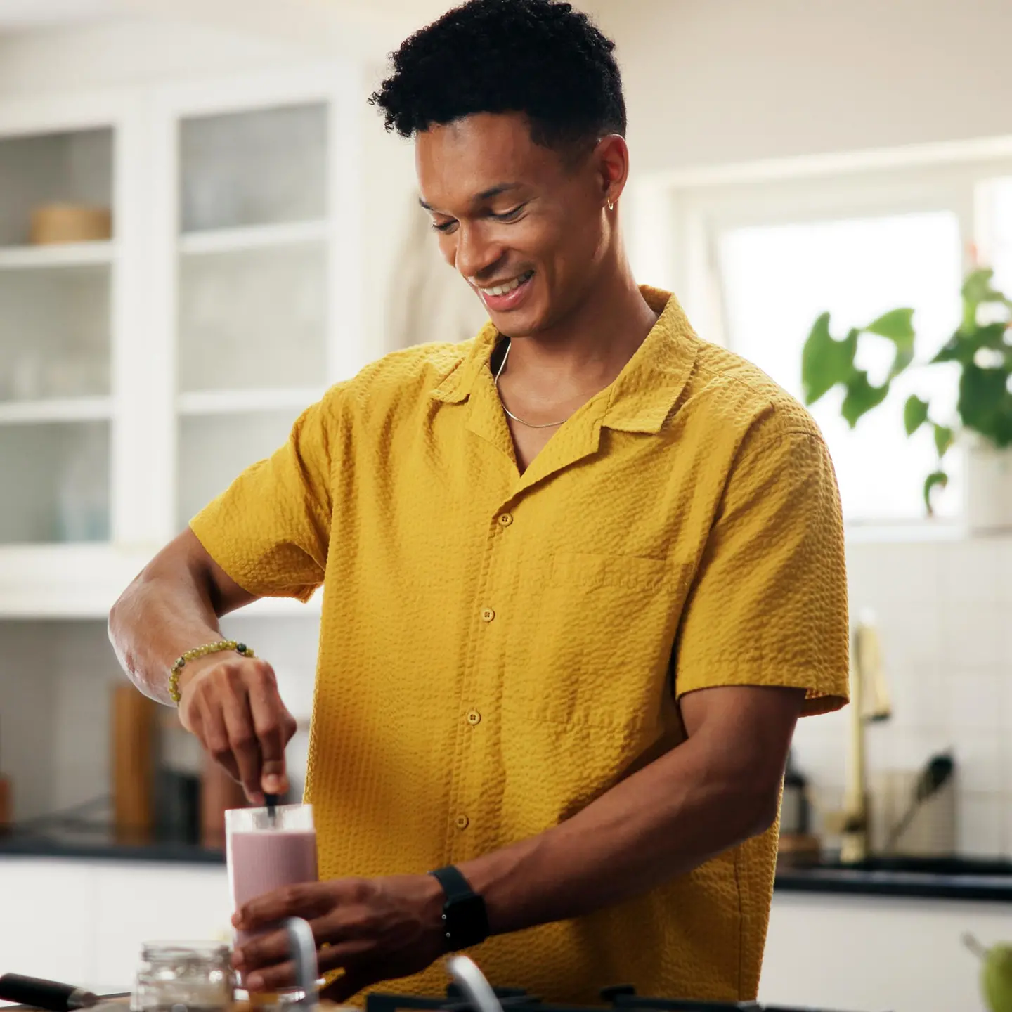 Proteinreiche Lebensmittel: Junger Mann bereitet sich in einer Küche einen Protein-Shake zu