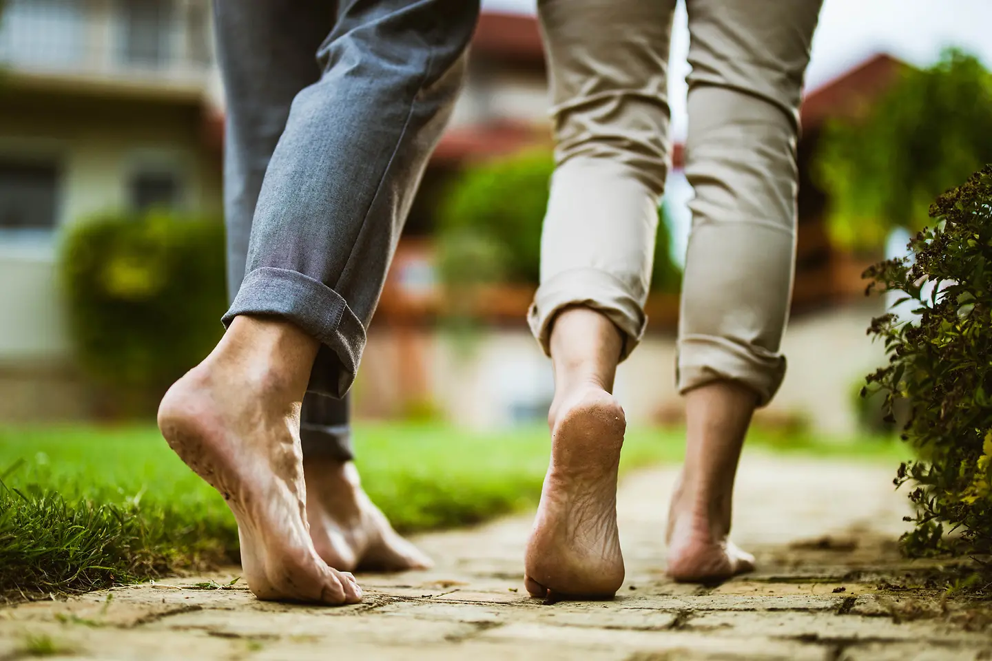 Paar geht beim Tai-Chi-Walking barfuß über einen gepflasterten Weg