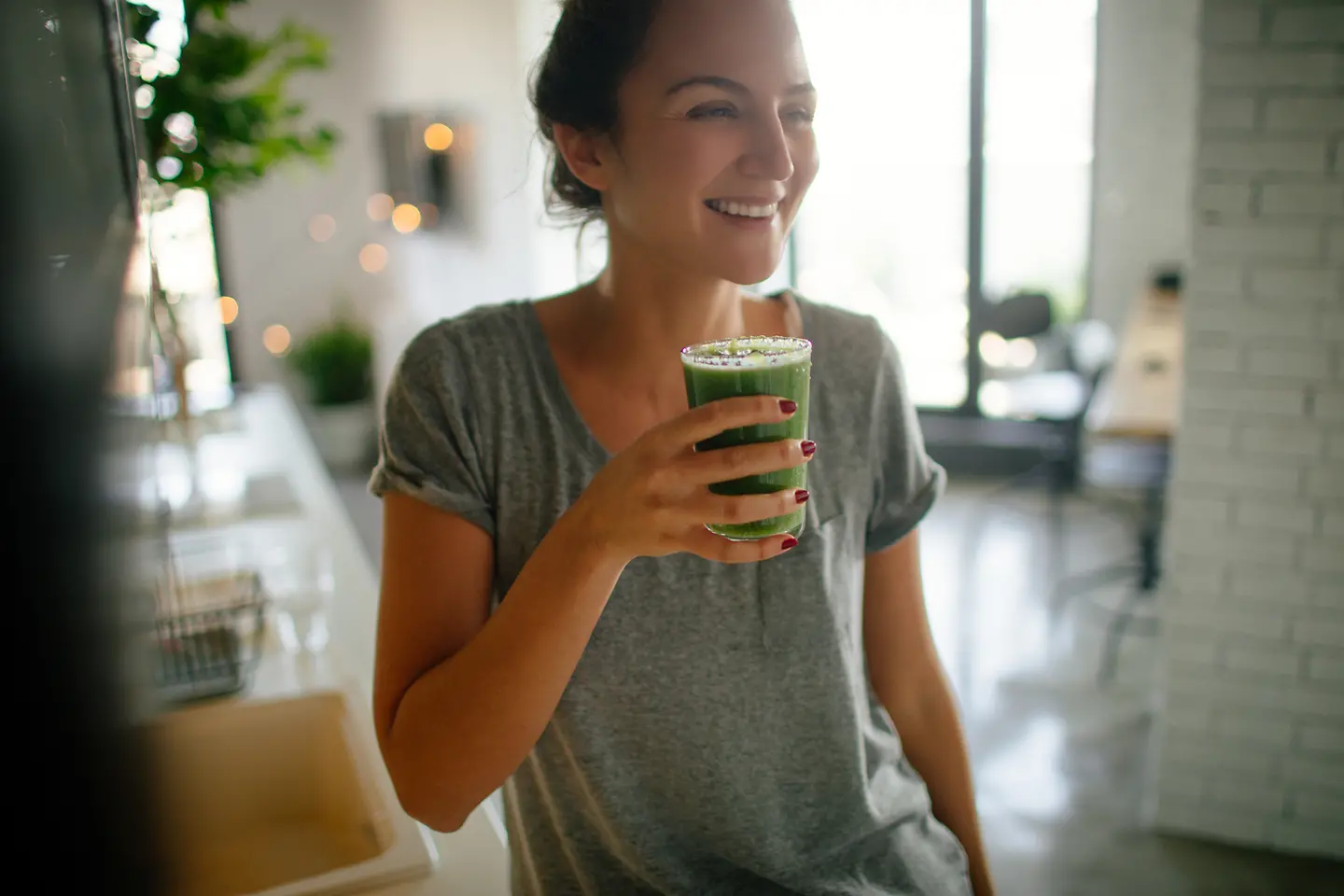 Junge lächelnde Frau trinkt einen Matcha