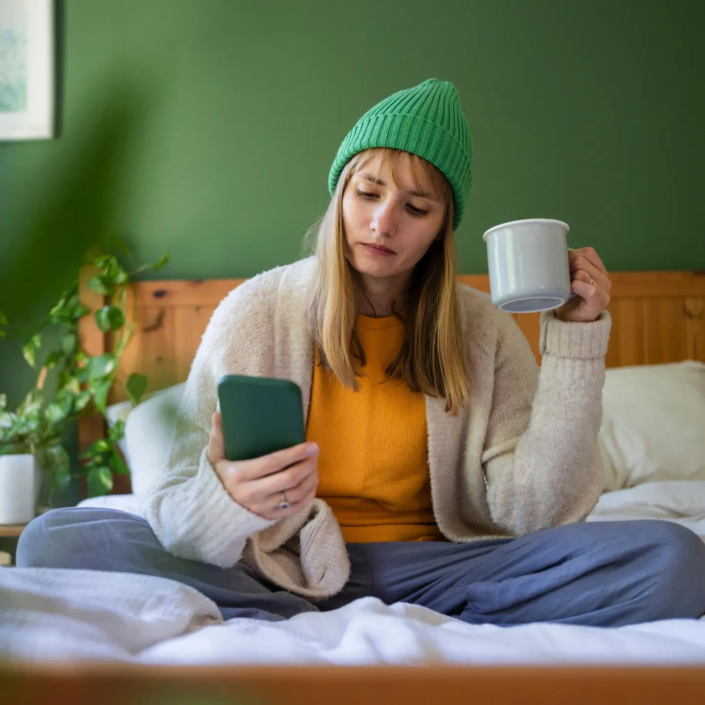 Eine junge Frau verwendet den Teledoktor. Sie hält eine Teetasse in der Hand und ist offensichtlich erkältet