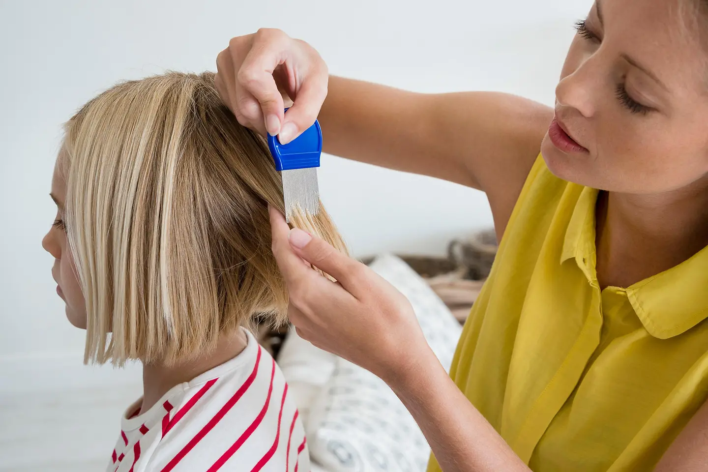 Mutter durchkämmt die Haare ihrer Tochter mit einem Läusekamm