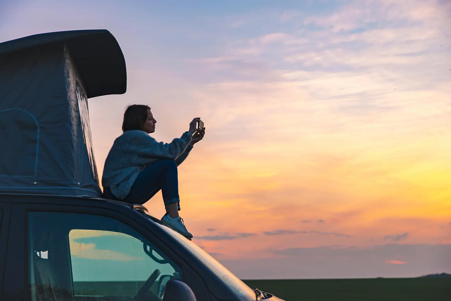 Frau sitzt auf einem Van und macht ein Foto