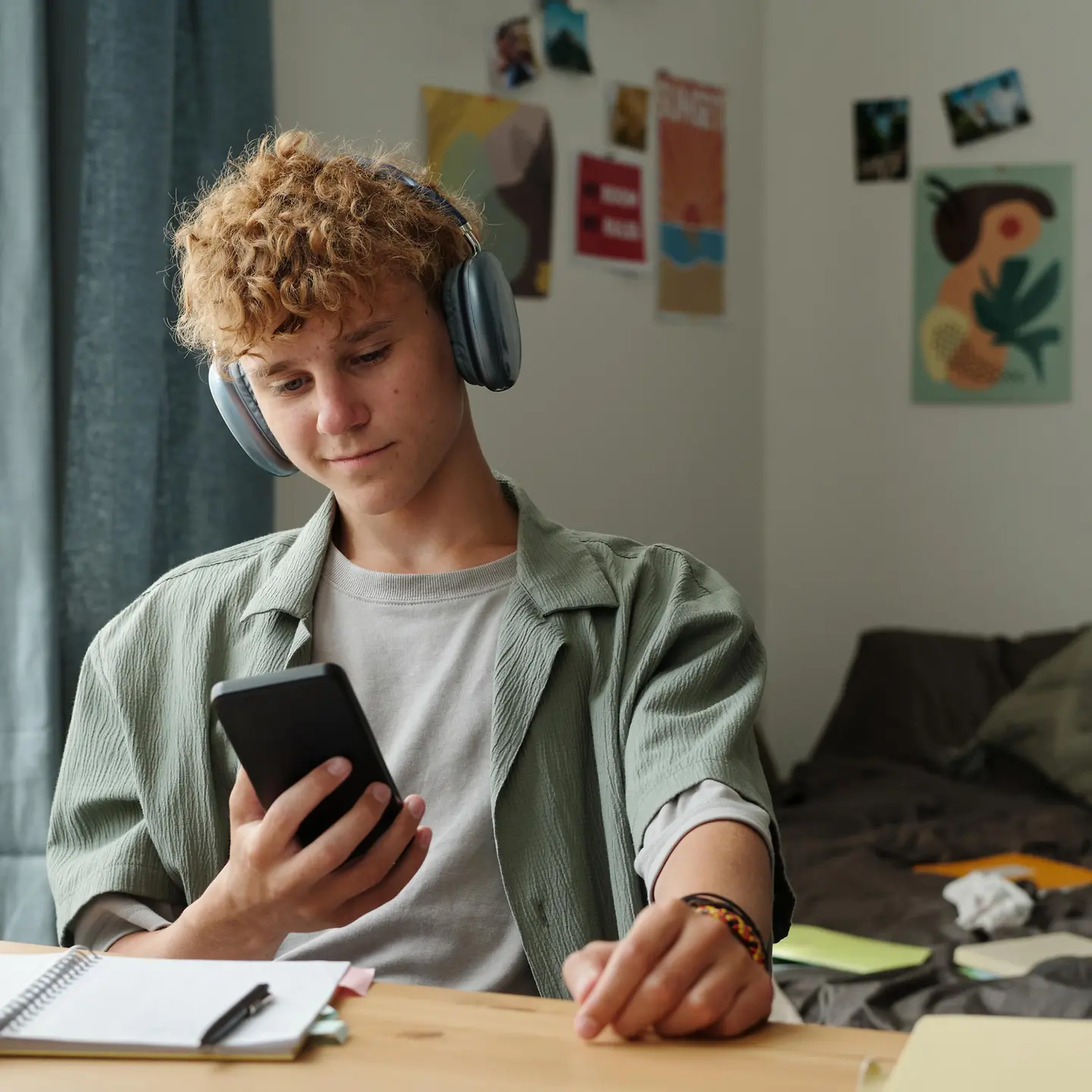 Multitasking: Junger Mann arbeitet, hört Musik und schaut gleichzeitig auf sein Handy