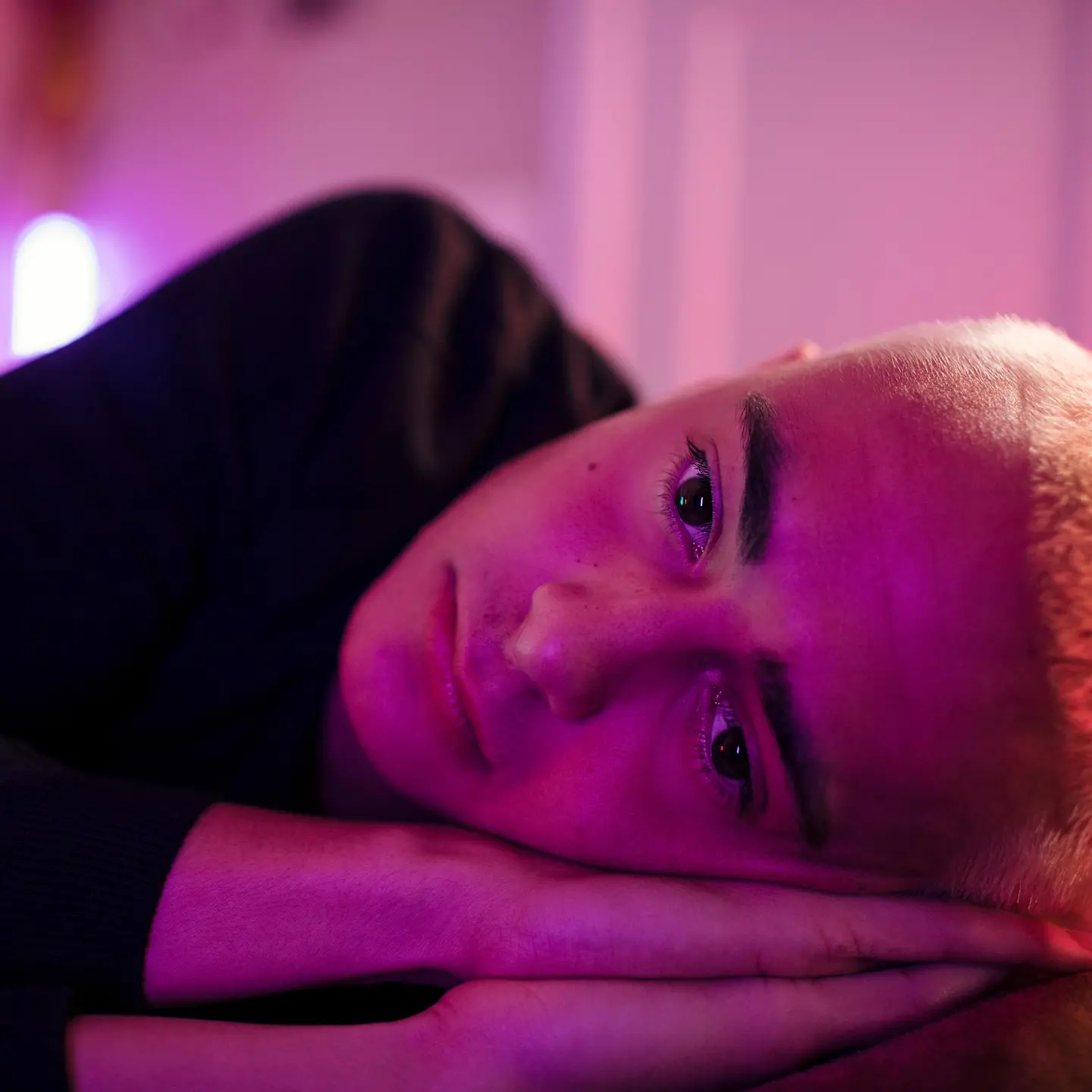 FOMO: Junger Mann mit kurzen Haaren liegt im Bett und schaut besorgt