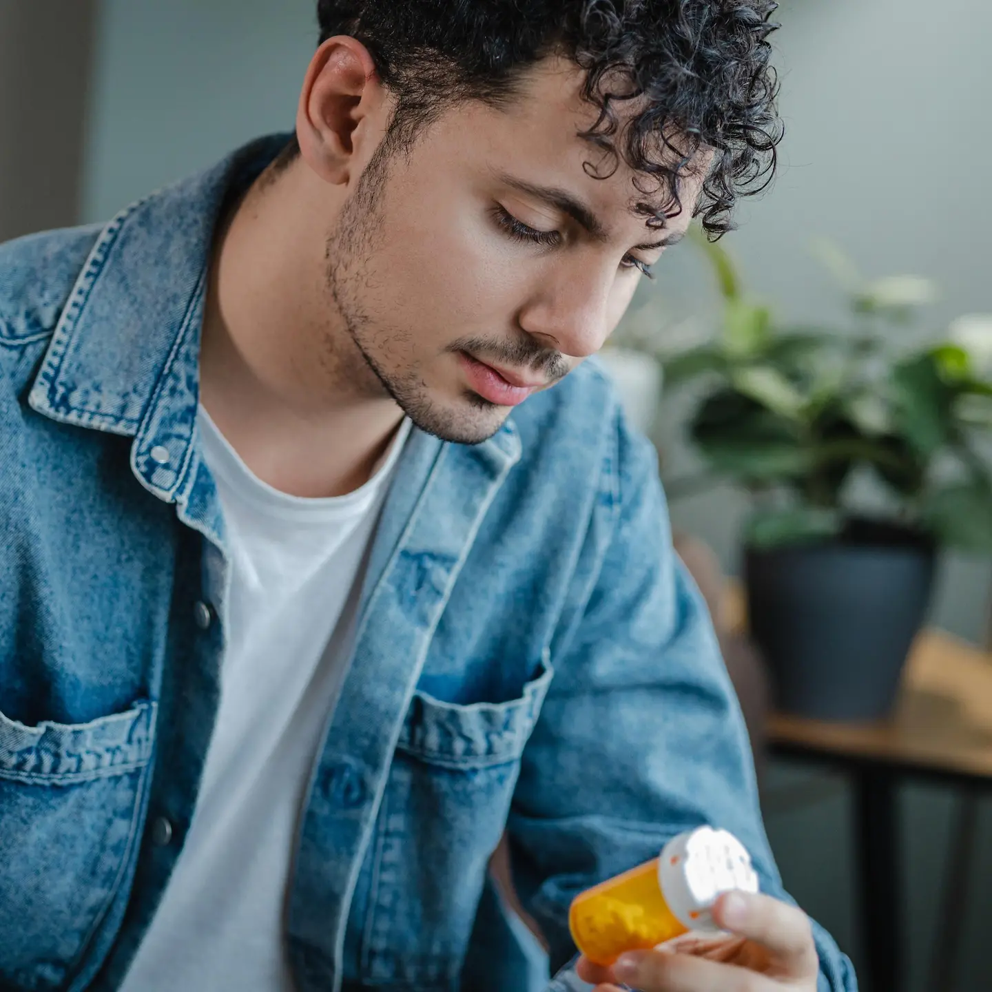 Omega 3: Ein junger Mann schaut nachdenklich Dose mit Kapseln